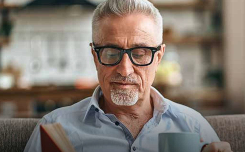 Retirement person relaxing reading a book holding a mug